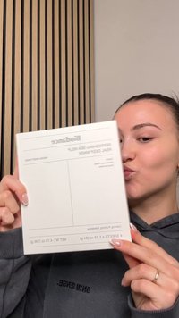 Hvid emballage mærket "Replenishing Sea Mask" med grå accenter og dimensioner. Glat tekstur, rektangulær form, holdt i hænder.