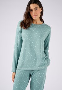 Pyjama vert clair à manches longues et pantalons, avec des motifs de croissant de lune et de points blancs ; en mélange de coton doux et coupe décontractée.