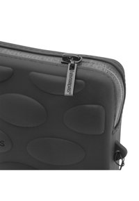 Pouch in silicone nero con texture ovale in rilievo, chiusura con zip e linguetta con marchio. Superficie liscia e bordi arrotondati per un design elegante.