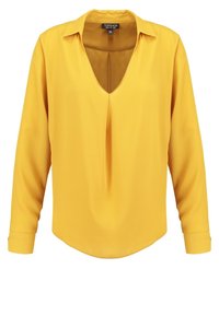 Blouse jaune à manches longues avec col en V, en tissu lisse, présentant un pli avant et une coupe décontractée. L'ourlet est arrondi.