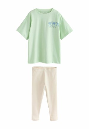 Světlezelené bavlněné tričko s modrou grafickou potiskem a krátkými rukávy, v kombinaci s krémově zbarvenými, texturovanými legínami.