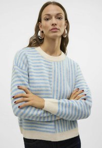 Maglione a righe blu chiaro e crema con una texture morbida, scollo a girocollo e polsini e fondo a costine, con righe di larghezze variabili.