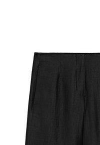 Pantaloni neri a vita alta con una vestibilità rilassata e una sottile texture, progettati per occasioni casual o eleganti. Non sono visibili chiusure.