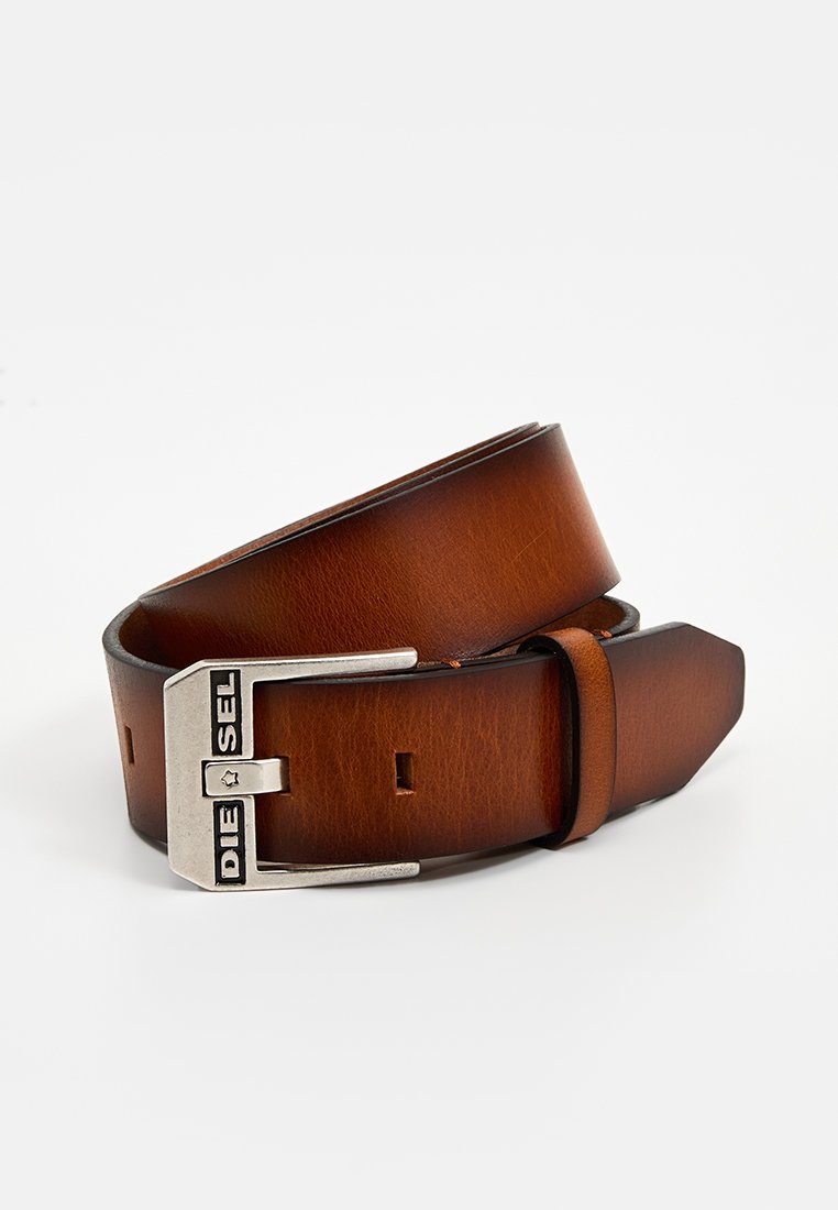 Bruine leren riem met een matte afwerking, voorzien van een zilverkleurige metalen gesp met de inscriptie "DIESEL." De riem heeft een rechte snit en een minimalistisch ontwerp.