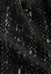 Tessuto in pizzo nero con intricati motivi floreali e a spirale, caratterizzato da una trama delicata e simile a una rete, con finiture curate in tutto il suo insieme.