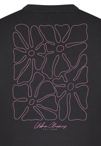 Tissu noir avec un dessin en ligne continue rose de quatre grandes fleurs abstraites et le texte « Urban Classics EST. 2005 » en dessous.