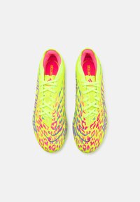 Des chaussures de football jaunes vives avec un motif léopard en rose et bleu. Conception légère avec des lacets, surface texturée et intérieur rembourré.