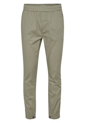 Helle olivgrüne Hose mit elastischem Bund und Kordelzug. Besitzt anliegende Beine und Knopfärmeln an den Knöcheln. Glatte Baumwolltextur.