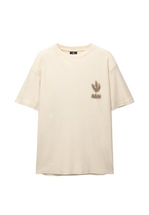 Tejfehér, rövid ujjú póló, pamutból, bordázott textúrával. A bal mellen barna hímzett logó részlet található.