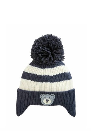 Knit kapa z mornarsko modrimi in belimi črtami, z velikim cofom na vrhu in sivo-belim obližem medvedjega obraza na sprednji strani.