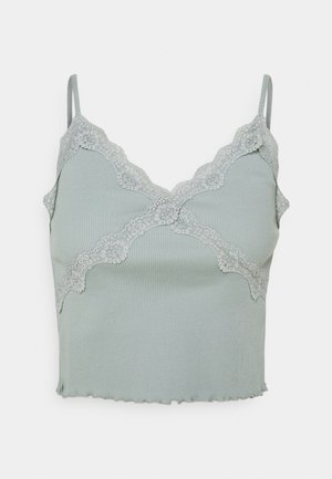 Hellgrünes, geripptes, kurzes Camisole mit Spitzenbesatz am Ausschnitt und dünnen Schulterträgern auf weißem Hintergrund.