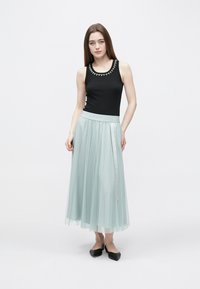 Fekete trikó gyöngyös nyakrúddal, világos menta zöld pliszírozott maxi szoknyával párosítva. A szett fekete lapos cipővel egészül ki.