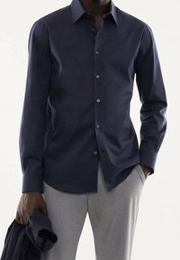 Camicia button-up blu navy con maniche lunghe, realizzata in tessuto liscio, con colletto e chiusura con bottoni classica. Tessuto leggero.