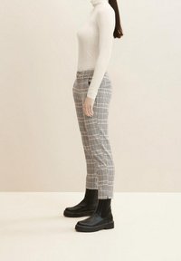 Tajt vit polo, rutiga gråbyxor och svarta ankelstövlar. Slät tyg, strukturerad design och kontrasterande mönster.