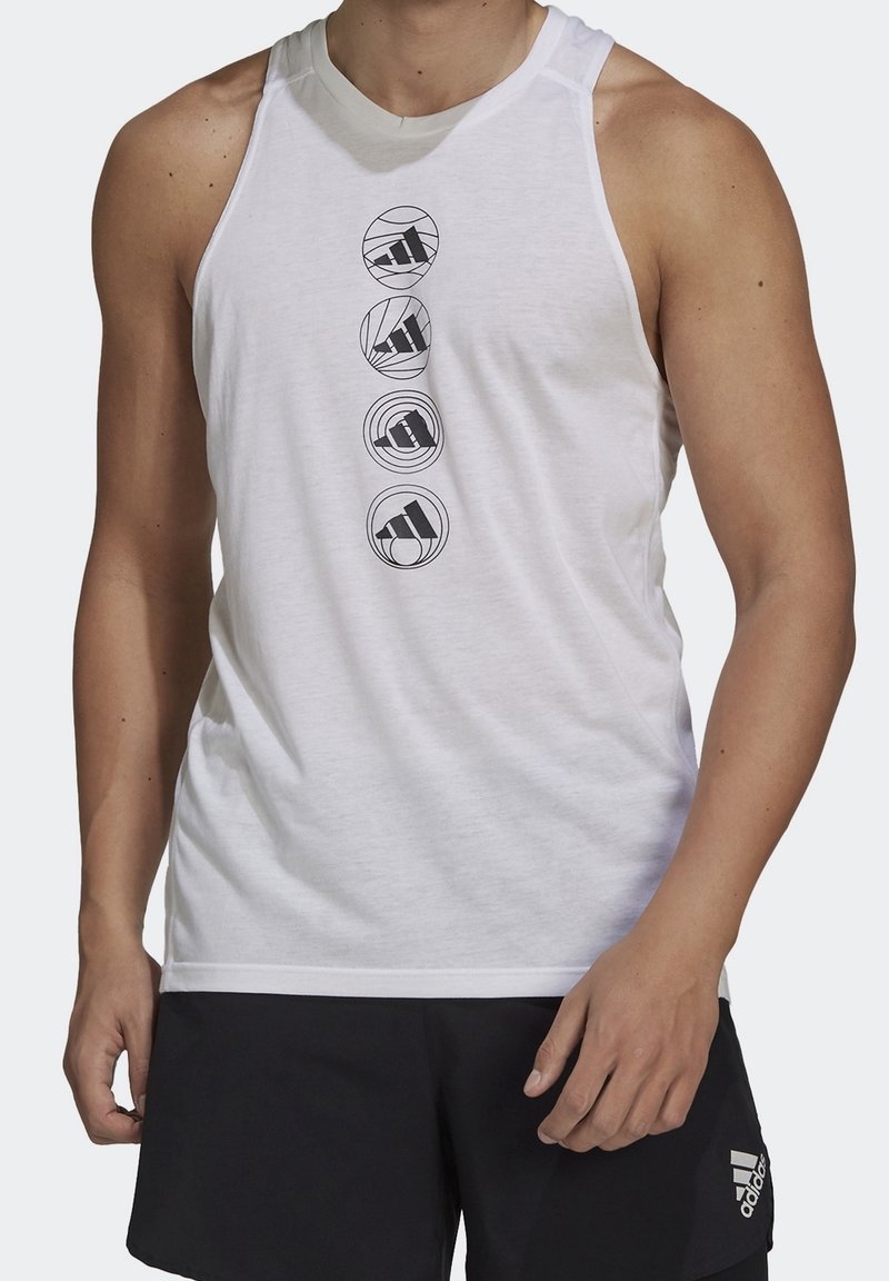 Homme portant un débardeur blanc sans manches avec quatre logos noirs Adidas en cercles au centre et un short noir avec logo Adidas sur la jambe gauche.