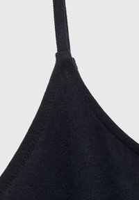 Camiseta negra de tirantes finos, con una textura suave y un diseño ajustado, que resalta una estética simple y minimalista.
