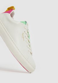 Zapatilla blanca de piel con acentos en verde pastel, rosa y amarillo. Tiene cordones planos y una suela texturizada, con el logo de la marca en un lado.