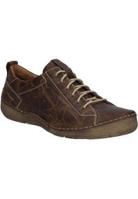 Sneaker en cuir marron avec une finition texturée, bout rond et lacets beige. Il présente une semelle en caoutchouc brun clair et des accents de couture visibles.