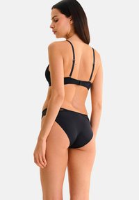 Ensemble de lingerie noire comprenant un soutien-gorge à bord en dentelle avec des bretelles réglables et des culottes taille haute assorties, le tout avec une finition lisse.