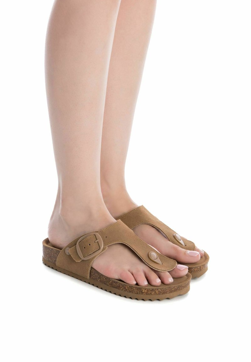 Sandalias de ante marrón con un lazo para los dedos, hebilla ajustable y suela texturizada. Su diseño abierto destaca los pies y proporciona transpirabilidad.