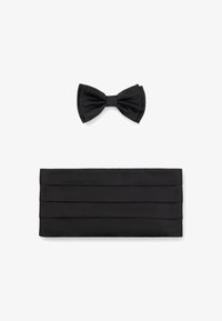 Pajarita negra y bolsa negra con plisados, ambas hechas de tela suave. La bolsa presenta plisados horizontales y una forma rectangular.