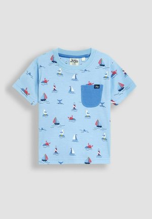 Vaaleansininen puuvillapaita, jossa on tasku, koristeltu värikkäillä purjeveneillä, merieläimillä ja aalloilla leikkisässä printissä.