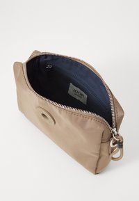 Borsa in nylon beige con chiusura a zip e interno blu navy. Presenta un emblema circolare e una piccola tasca con zip interna.