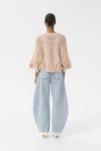Lichtroze gebreide trui met een textuurdesign, gecombineerd met oversized lichtblauwe denim jeans. Draag het met puntige witte hakken.