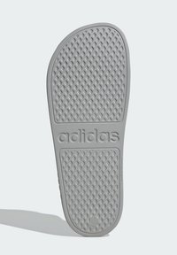 Šedá gumová podrážka sandálů s diamantovým vzorem, strukturovaným povrchem a vyraženým názvem značky "adidas" výrazně zobrazeným.