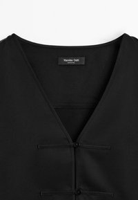Zwarte blouse met een v-hals ontwerp, twee knoopdetails en een gladde stofstructuur. Label leest "Massimo Dutti."