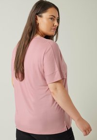 Rosa bomullströja med korta ärmar, avslappnad passform, rundhalsad, sidofickor i nederkant, slät textur och avslappnad design.