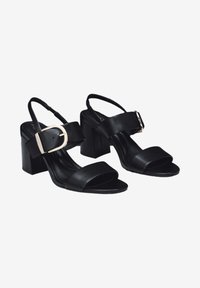 Schwarze High-Heel-Sandale aus Leder mit offener Spitze, breitem Riemen über dem Fuß, verstellbarem Slingback-Riemen und einem goldfarbenen Schnallendetail.