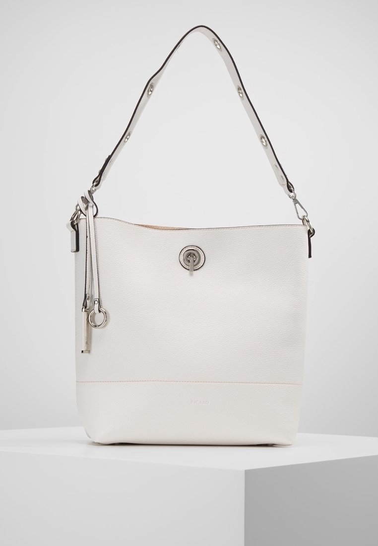 Sac seau en cuir blanc avec un fermoir tournant argenté, une bandoulière réglable et deux pampilles en cuir suspendues avec des anneaux argentés.