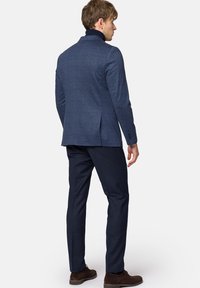 Granatowy, w kratę żakiet z wysokim kołnierzem, zestawiony z ciemnogranatowymi spodniami. Gładka tekstura z subtelnymi detalami na tkaninie.