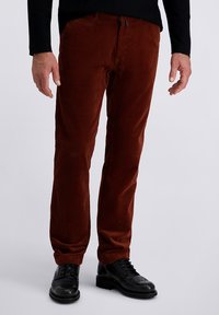 Brown corduroy trousers with a straight fit, featuring textured vertical ridges, classic pockets, and a zip fly, paired with black dress shoes.