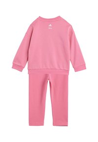 Rosa sweatshirt och byxor set, tillverkat av mjukt tyg. Har en rundad halsringning, långa ärmar och en logotyp på baksidan.