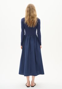 Rochie lungă de culoare navy, cu un top strâmt din material ribbed și o fustă fluidă. Materialul pare ușor și are o textură netedă.