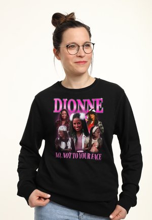 Kobieta w okularach nosząca czarną bluzę z wieloma obrazami Dionne z filmu Clueless i napisem "Dionne, nie, nie w twarz."