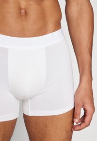 Weiße Baumwoll-Boxershorts mit einem weichen, elastischen Bund, der das geprägte "Levi's"-Logo trägt; glatte Textur und passgenaue Form.