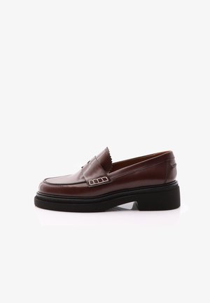 Mocassino in pelle marrone con punta rotonda, suola chunky nera a contrasto e accenti decorativi in argento sulla tomaia. Texture liscia.