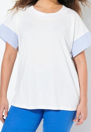 Witte T-shirt met blauwe gestreepte korte mouwen en een ronde hals. De stof lijkt zacht met een relaxte pasvorm. Gecombineerd met blauwe broek.