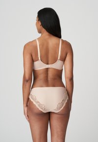 Set di reggiseno e brasiliana beige con bordo in pizzo, caratterizzato da spalline regolabili, tessuto liscio e bordo ondulato sulla brasiliana.