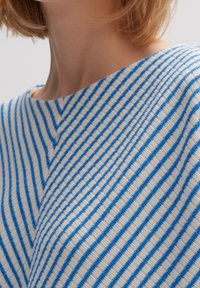 Pasiasty sweter dzianinowy z naprzemiennymi niebieskimi i białymi liniami, o miękkiej fakturze i szerokim dekolcie. Kąt widzenia ukazuje szczegóły górnej części ramienia.