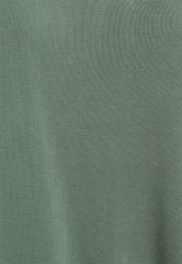 Tissu vert au toucher lisse, présentant un motif finement strié. D'épaisseur moyenne, idéal pour un style décontracté ou pour superposer.