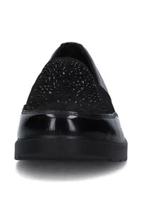 Scarpe nere slip-on con tomaia texturizzata arricchita da piccoli chiodini, una finitura liscia e lucida attorno alla punta e suola piatta in gomma.