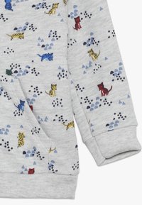 Felpa grigia con stampe di animali multicolori, tra cui leopardi gialli e rossi, con motivi triangolari blu e verdi e una finitura texturizzata.