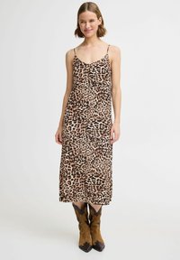 Abito maxi con stampa leopardata in tessuto leggero con spalline. Presenta una vestibilità fluida e una leggera lucentezza; abbinato a stivali da cowboy marroni.