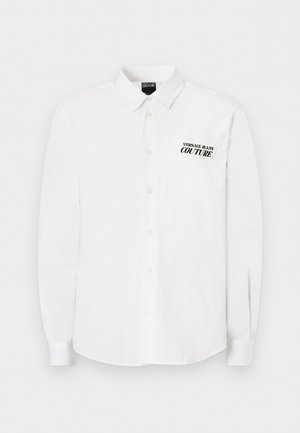 Valge pika varrukaga nööpidega särk kraega, millel vasakul rinnal on must "Versace Jeans Couture" tekstlogo.