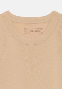 Beige bomulls tanktopp med rund halslinning, med glatt tekstur og ribbede kanter. Etiketts sier "FRIBOO" med størrelsesdetaljer.