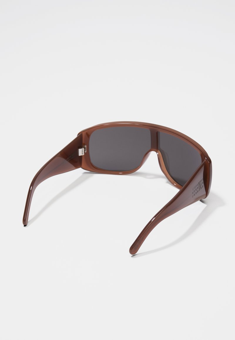 Braune Kunststoffsonnenbrille mit dunklen Gläsern, rechteckiger Form und breiten Bügeln. Die Bügel weisen dezente Markenembleme auf und haben eine glatte, glänzende Oberfläche.